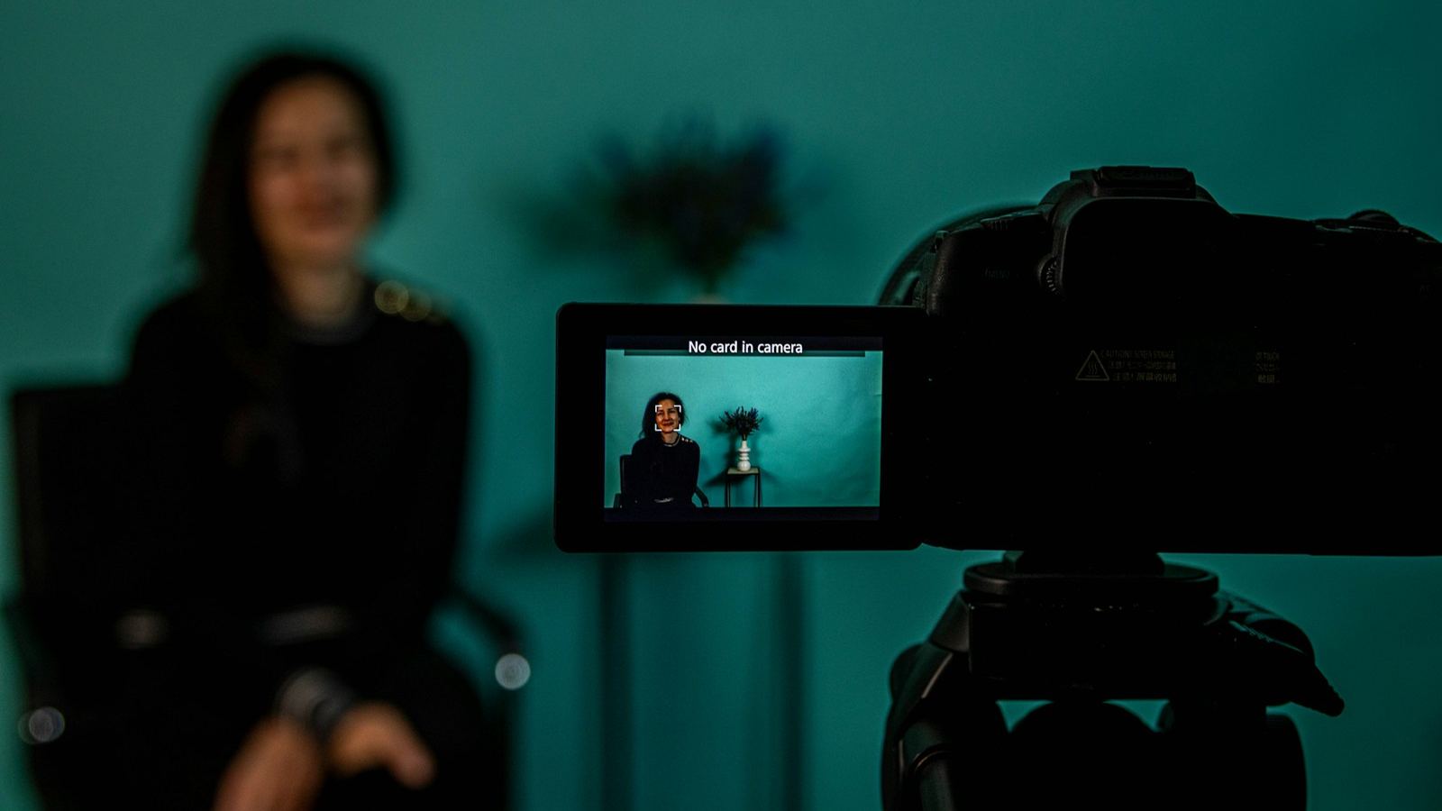 Camera and field monitor framing a subject against a teal background